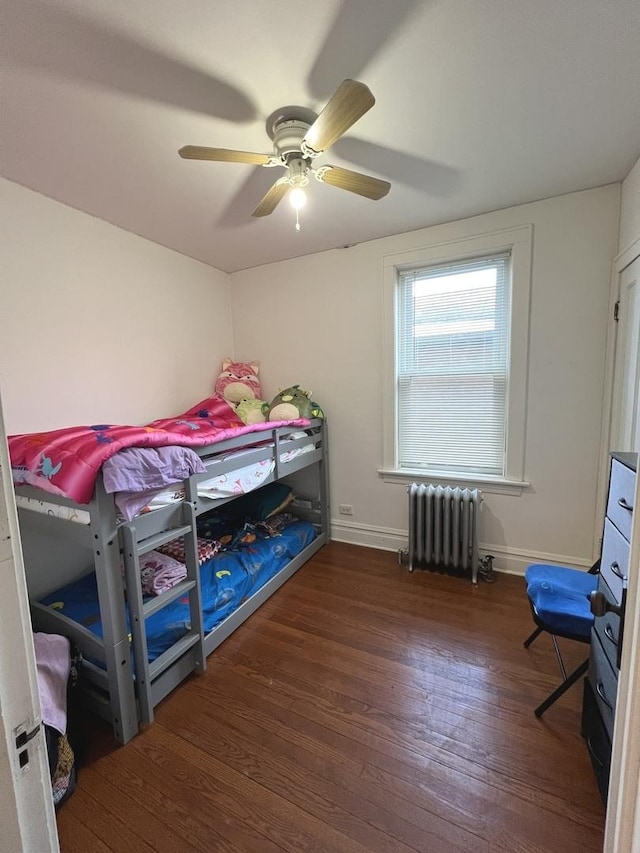 bedroom with radiator heating unit, dark hardwood / wood-style floors, and ceiling fan