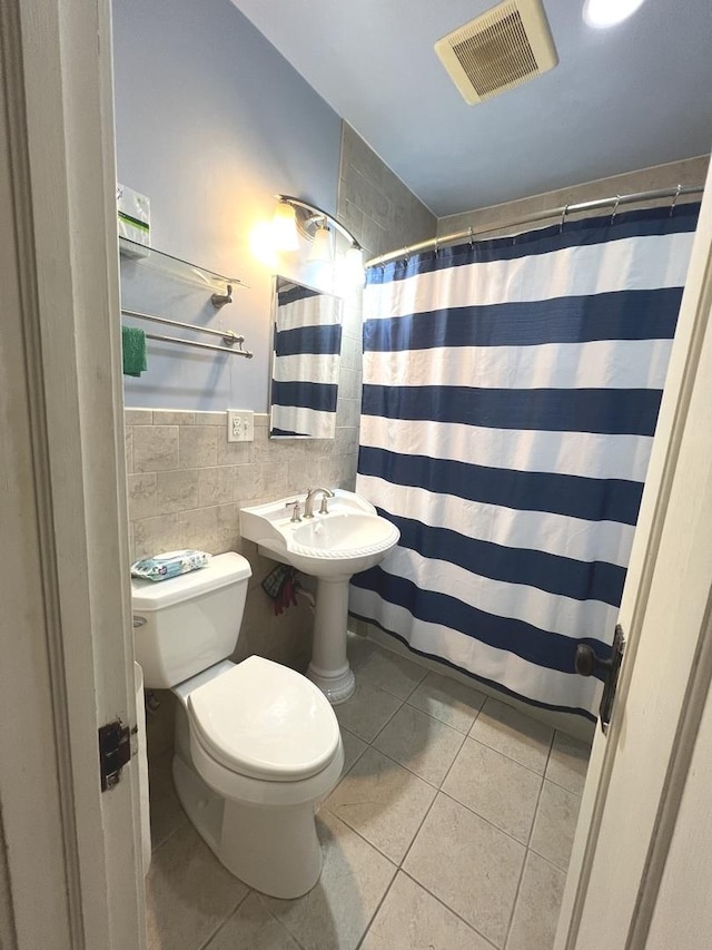 bathroom with tile patterned floors, toilet, a shower with shower curtain, and tile walls