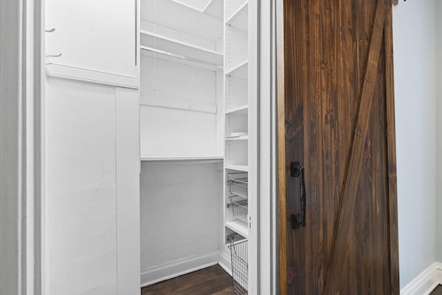 spacious closet with dark wood finished floors and attic access