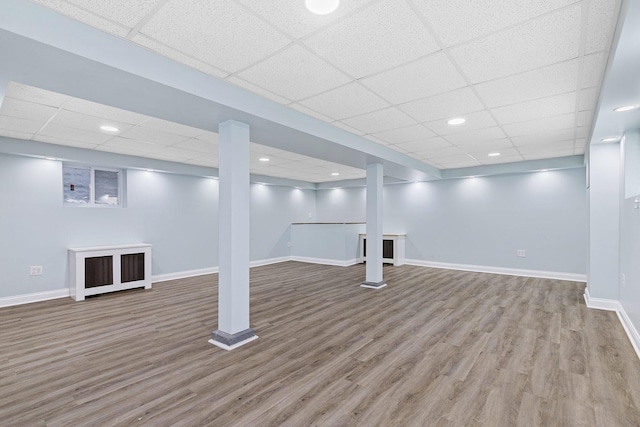 finished basement featuring recessed lighting, a drop ceiling, wood finished floors, and baseboards