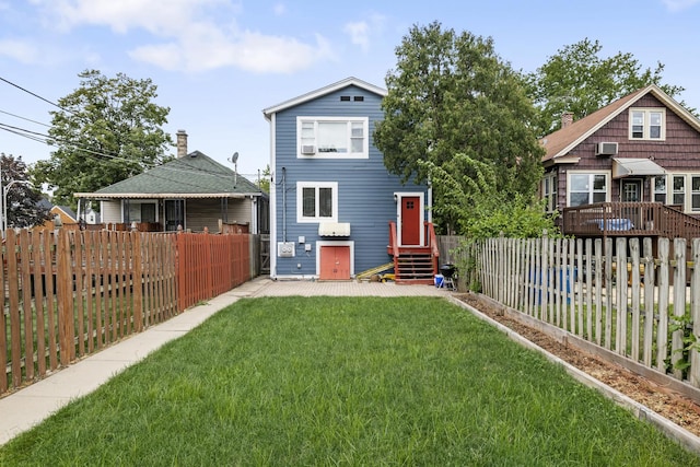 back of house with entry steps, a fenced backyard, and a yard