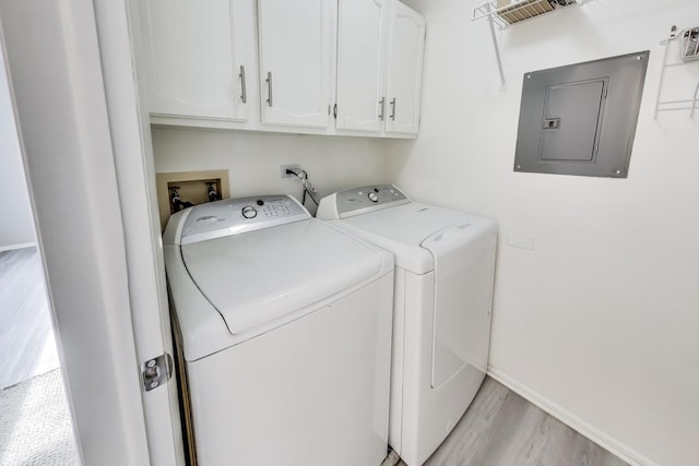 clothes washing area featuring washer and dryer, light hardwood / wood-style flooring, electric panel, and cabinets