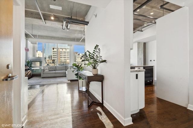 hallway with a view of city, track lighting, baseboards, and dark wood-style flooring