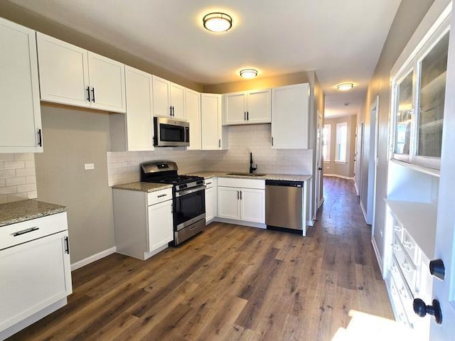 kitchen featuring stainless steel appliances, a sink, baseboards, white cabinets, and dark wood finished floors