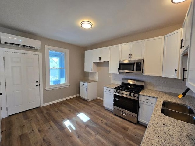 kitchen featuring an AC wall unit, appliances with stainless steel finishes, light stone countertops, dark wood-style floors, and tasteful backsplash