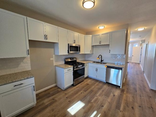 kitchen featuring appliances with stainless steel finishes, dark wood-type flooring, a sink, and white cabinetry