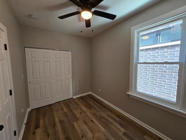 unfurnished bedroom with ceiling fan, dark wood-style flooring, a closet, and baseboards