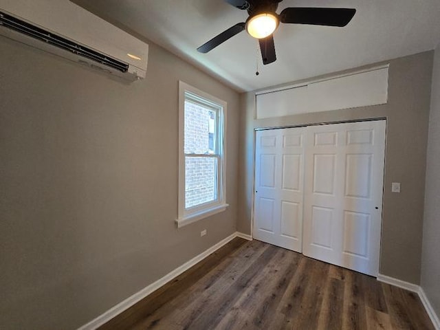 unfurnished bedroom featuring baseboards, dark wood finished floors, a ceiling fan, a closet, and a wall mounted AC