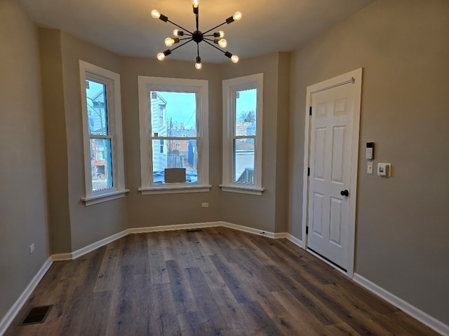 unfurnished dining area with an inviting chandelier, baseboards, visible vents, and dark wood-type flooring