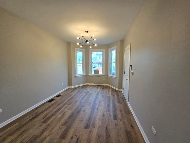 unfurnished dining area featuring visible vents, baseboards, dark wood finished floors, and a notable chandelier