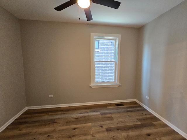 unfurnished room featuring dark wood-style floors, a ceiling fan, and baseboards