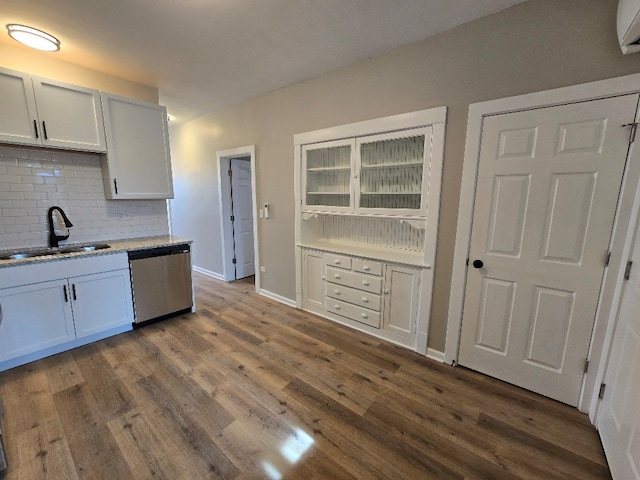 kitchen with baseboards, decorative backsplash, dark wood-type flooring, stainless steel dishwasher, and a sink