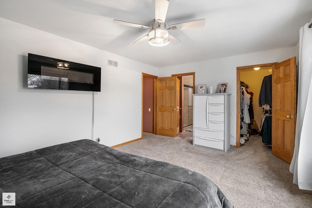 carpeted bedroom with ceiling fan, a walk in closet, and a closet