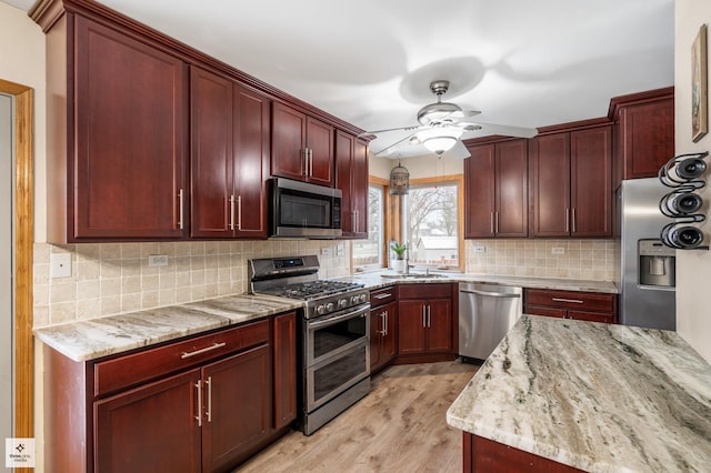 kitchen featuring light hardwood / wood-style flooring, ceiling fan, appliances with stainless steel finishes, backsplash, and light stone counters