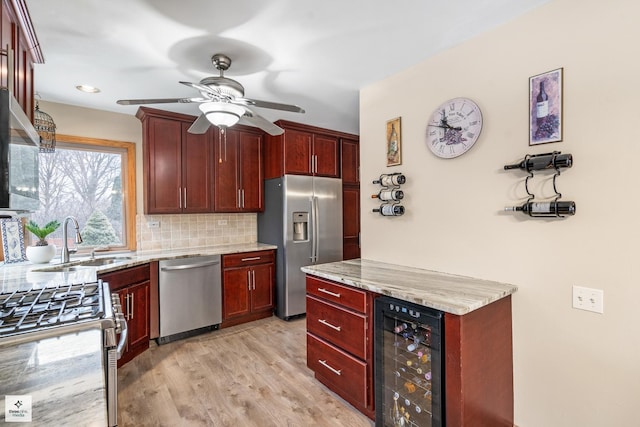 kitchen featuring tasteful backsplash, sink, wine cooler, stainless steel appliances, and light stone countertops