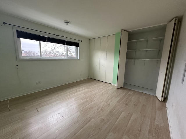 unfurnished bedroom featuring light hardwood / wood-style flooring and two closets