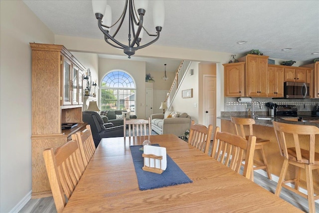 dining space featuring an inviting chandelier, light hardwood / wood-style floors, sink, and a textured ceiling