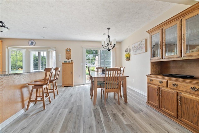 dining area featuring a healthy amount of sunlight, a chandelier, light hardwood / wood-style flooring, and a textured ceiling