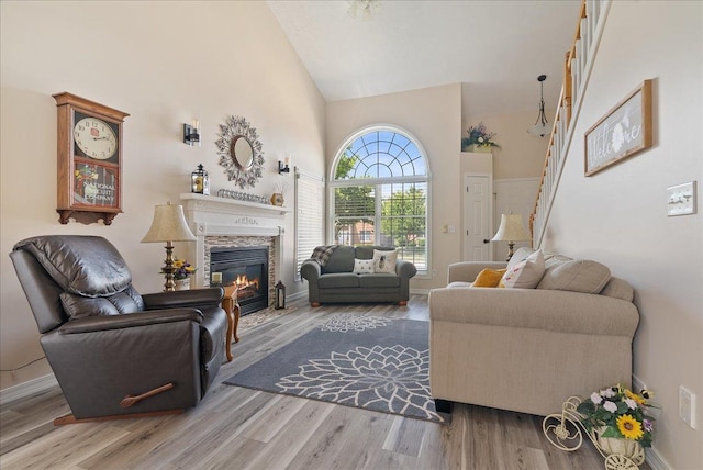 living room featuring hardwood / wood-style flooring, high vaulted ceiling, and a tile fireplace