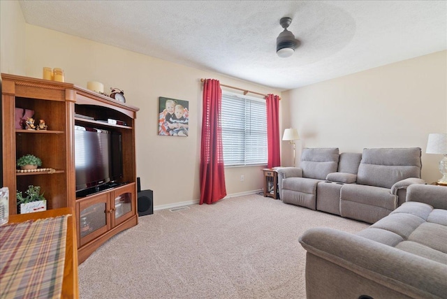 carpeted living room featuring ceiling fan and a textured ceiling