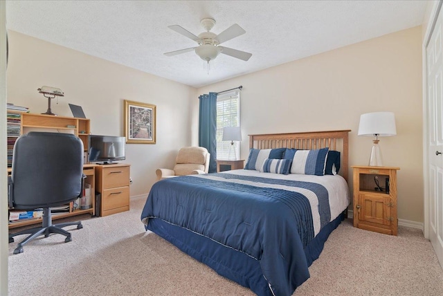 bedroom with light carpet, ceiling fan, and a textured ceiling