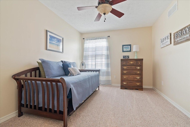 bedroom with ceiling fan, light carpet, and a textured ceiling