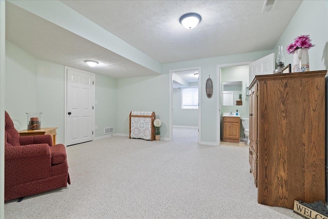 living area featuring light colored carpet and a textured ceiling