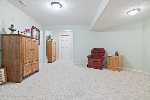 sitting room with light colored carpet and a textured ceiling