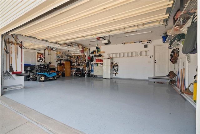 garage featuring a garage door opener, a workshop area, and white fridge