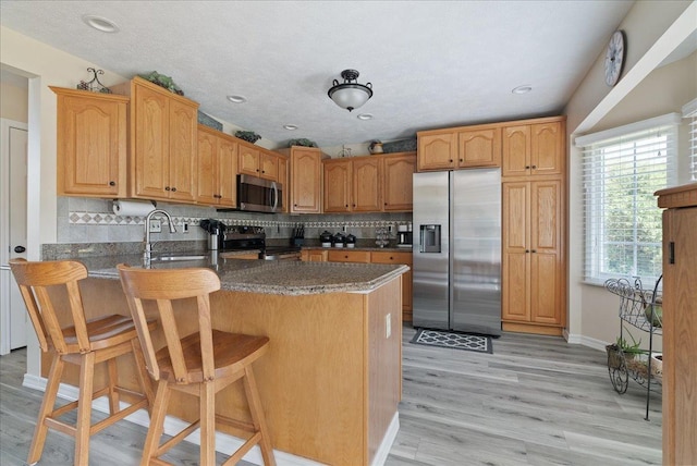 kitchen with stainless steel appliances, a breakfast bar, decorative backsplash, and kitchen peninsula