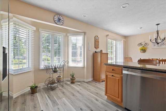 kitchen featuring an inviting chandelier, a textured ceiling, hanging light fixtures, light wood-type flooring, and stainless steel dishwasher