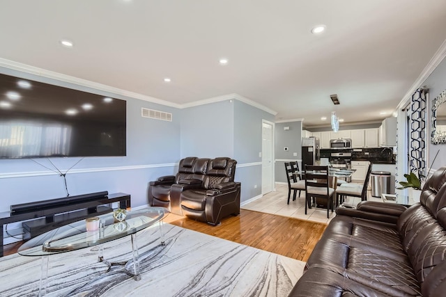 living room featuring sink, ornamental molding, and light wood-type flooring