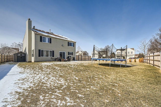 back of property featuring a trampoline and a storage shed