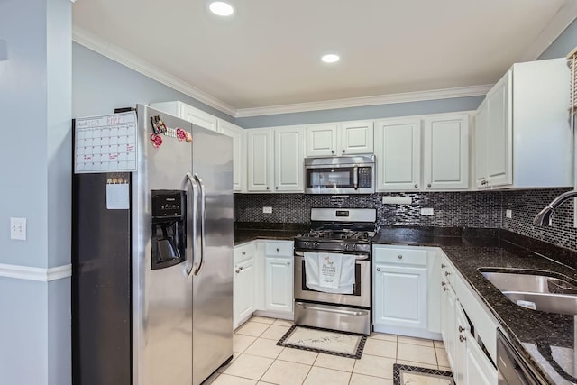 kitchen featuring sink, light tile patterned floors, appliances with stainless steel finishes, white cabinetry, and dark stone counters