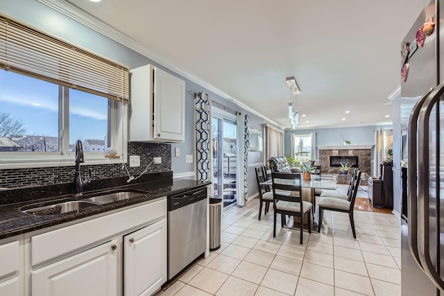 kitchen with light tile patterned flooring, sink, dark stone countertops, appliances with stainless steel finishes, and white cabinets