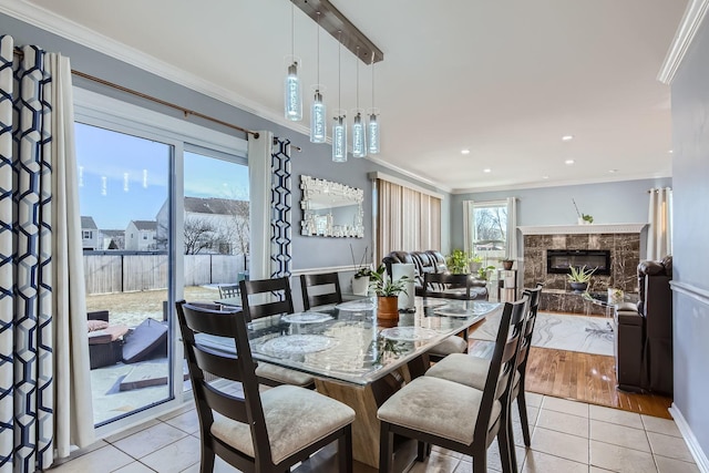 dining space with a premium fireplace, ornamental molding, and light tile patterned floors