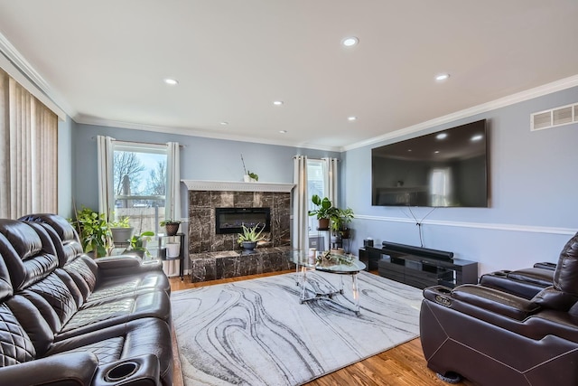 living room with wood-type flooring, ornamental molding, and a fireplace