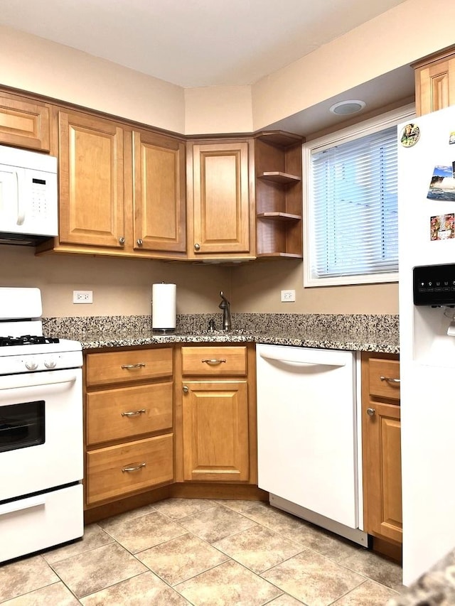 kitchen featuring white appliances, stone countertops, sink, and light tile patterned floors