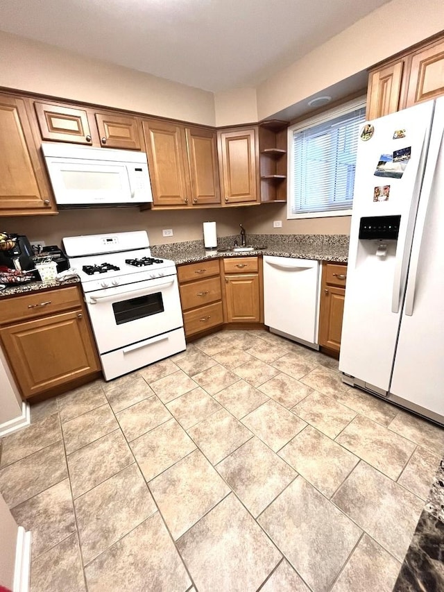 kitchen with white appliances, stone countertops, sink, and light tile patterned floors