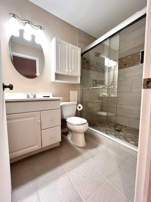 bathroom featuring vanity, a shower with shower door, tile patterned floors, and toilet