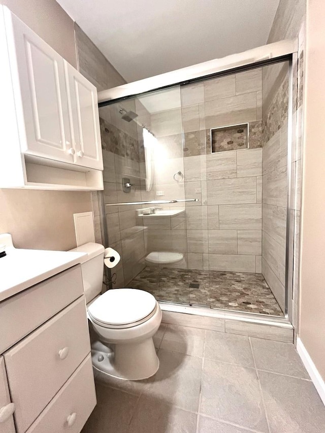 bathroom with an enclosed shower, vanity, and toilet