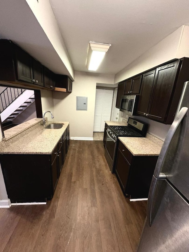 kitchen featuring appliances with stainless steel finishes, dark hardwood / wood-style floors, sink, electric panel, and light stone counters