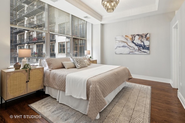 bedroom with dark hardwood / wood-style flooring, crown molding, and a raised ceiling