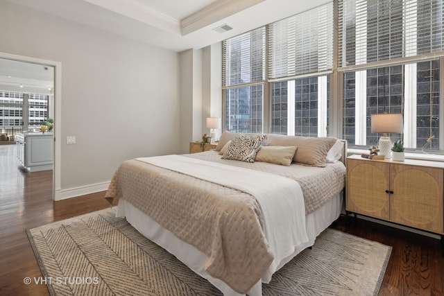 bedroom featuring a raised ceiling, ornamental molding, and dark hardwood / wood-style flooring