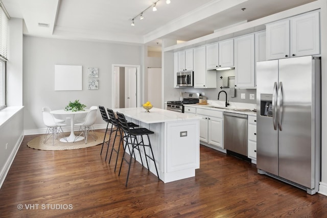 kitchen with sink, white cabinetry, appliances with stainless steel finishes, a tray ceiling, and a kitchen island