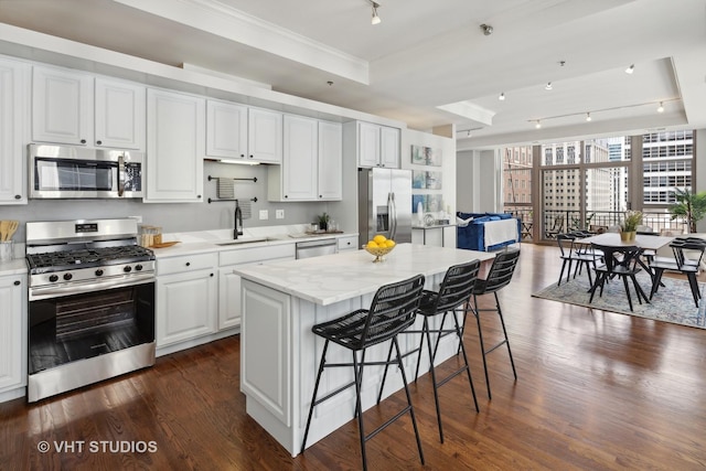 kitchen featuring stainless steel appliances, white cabinetry, a kitchen island, and dark hardwood / wood-style flooring