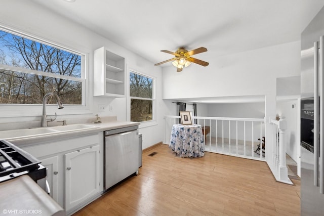 kitchen with white cabinetry, sink, stainless steel dishwasher, ceiling fan, and light hardwood / wood-style floors