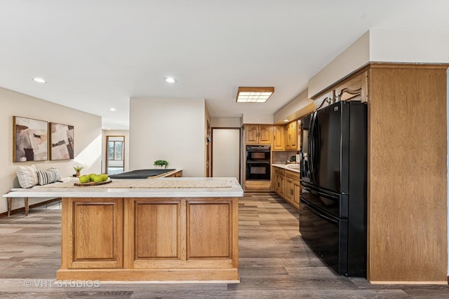 kitchen with black appliances, light countertops, light wood-style flooring, and a center island