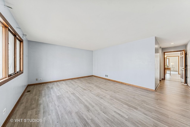 empty room featuring wood finished floors, visible vents, and baseboards