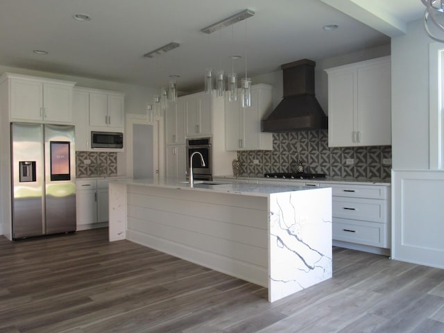 kitchen with premium range hood, an island with sink, white cabinetry, sink, and stainless steel appliances